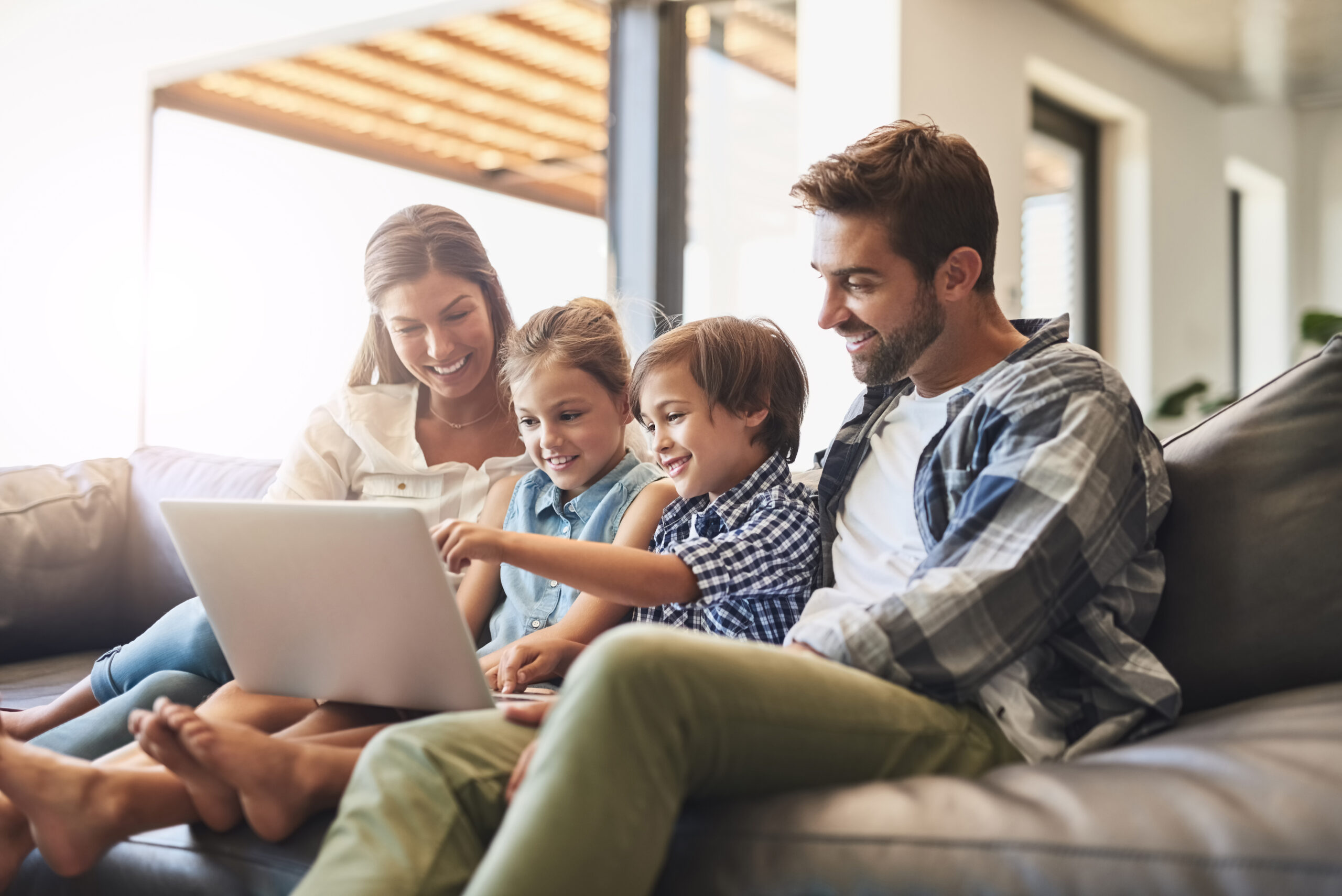 Connected online and as a family. Shot of a mother and father using a laptop with their son and daughter on the sofa at home.